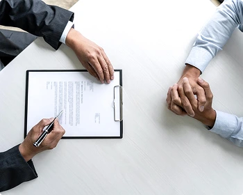 A top-down shot showing the signing of a document on a white table between two people