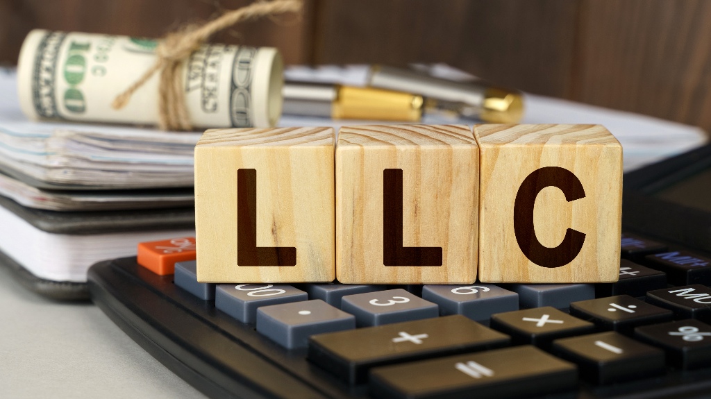 On the table are money, a calculator, a notebook and cubes with the inscription - LLC