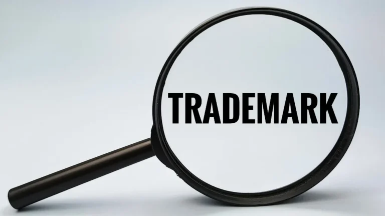 Magnifying glass enlarging the word "TRADEMARK" on a light background.